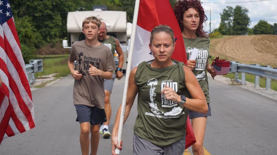 Runners carrying the American flag along a Kentucky road