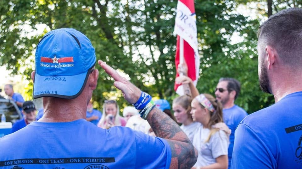 A runner salutes as the Honor and Remember flag passes